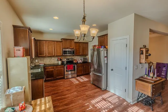 a kitchen with stainless steel appliances kitchen island granite countertop a refrigerator and a stove top oven
