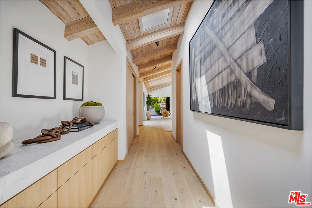 1508 Old Oak Road Los Angeles, CA 90049 - Photo 16 of 63 a hallway with painting on the wall and a wooden floor