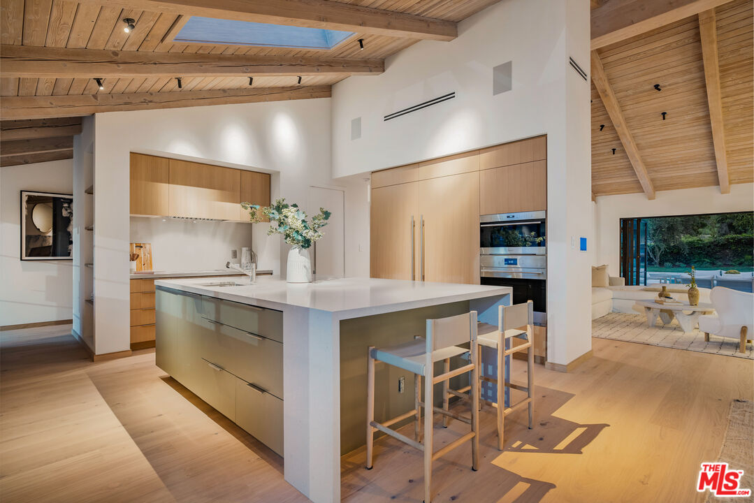 1508 Old Oak Road Los Angeles, CA 90049 - Photo 54 of 63 a kitchen with stainless steel appliances kitchen island granite countertop a table and chairs in it