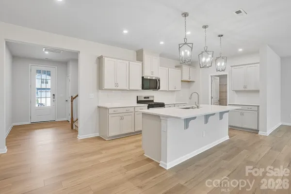 a kitchen with kitchen island granite countertop a sink cabinets and wooden floor