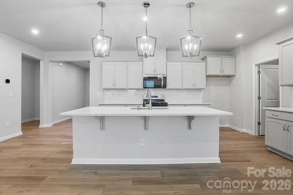 a kitchen with stainless steel appliances granite countertop a sink a refrigerator a center island a stove and wooden floor