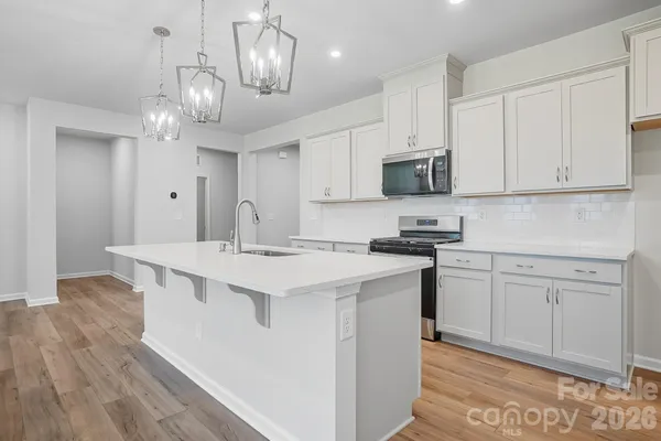 a kitchen with kitchen island granite countertop a sink a stove and cabinets