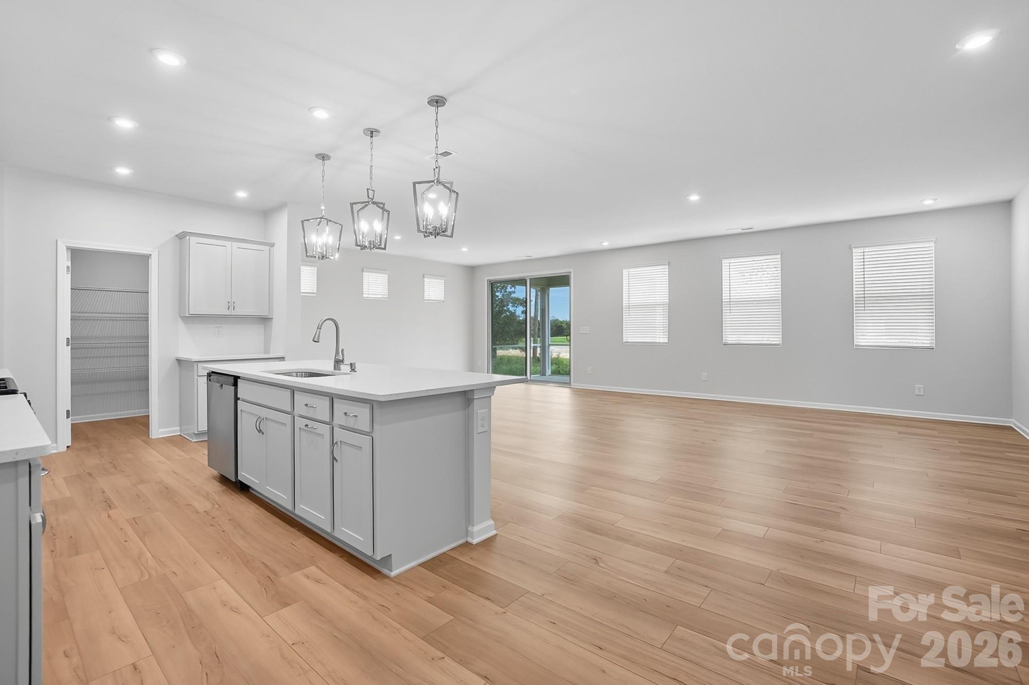 1505 Miriam Way Monroe, NC 28112 - Photo 8 of 29 a large white kitchen with kitchen island a large counter top space a sink stainless steel appliances and a window