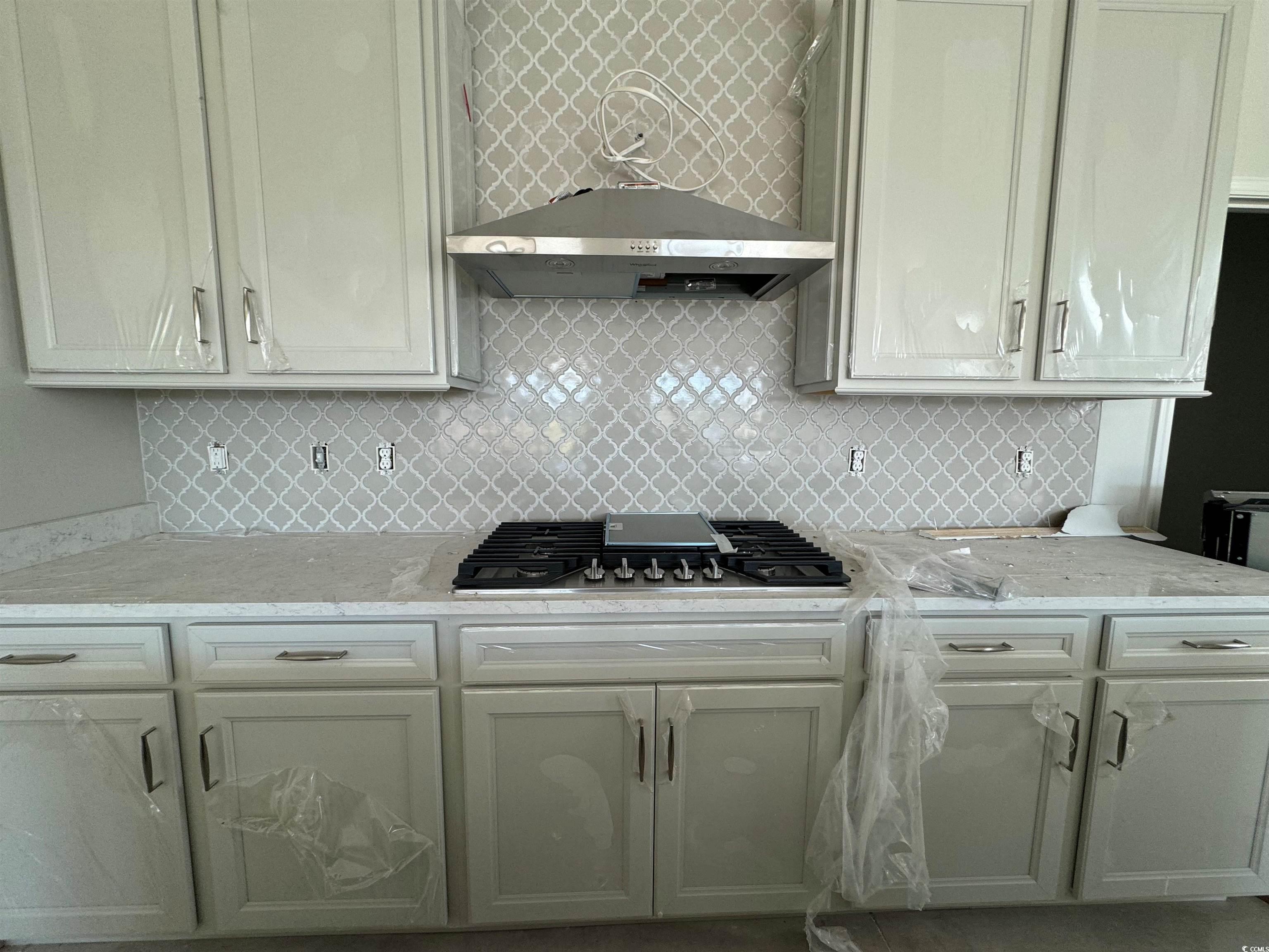Kitchen featuring tasteful backsplash, light stone