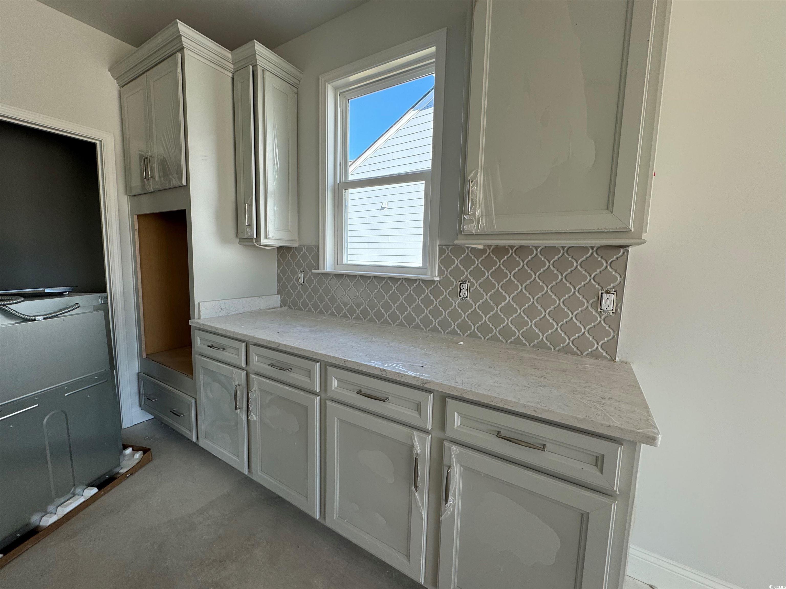 Kitchen featuring white cabinets, light stone coun