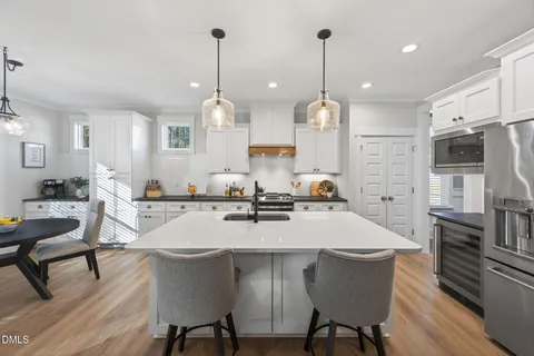 a large kitchen with a dining table chairs stainless steel appliances and cabinets