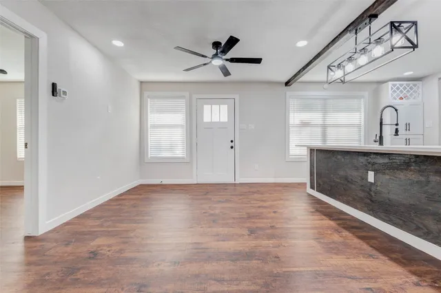 a view of an empty room with window and wooden floor