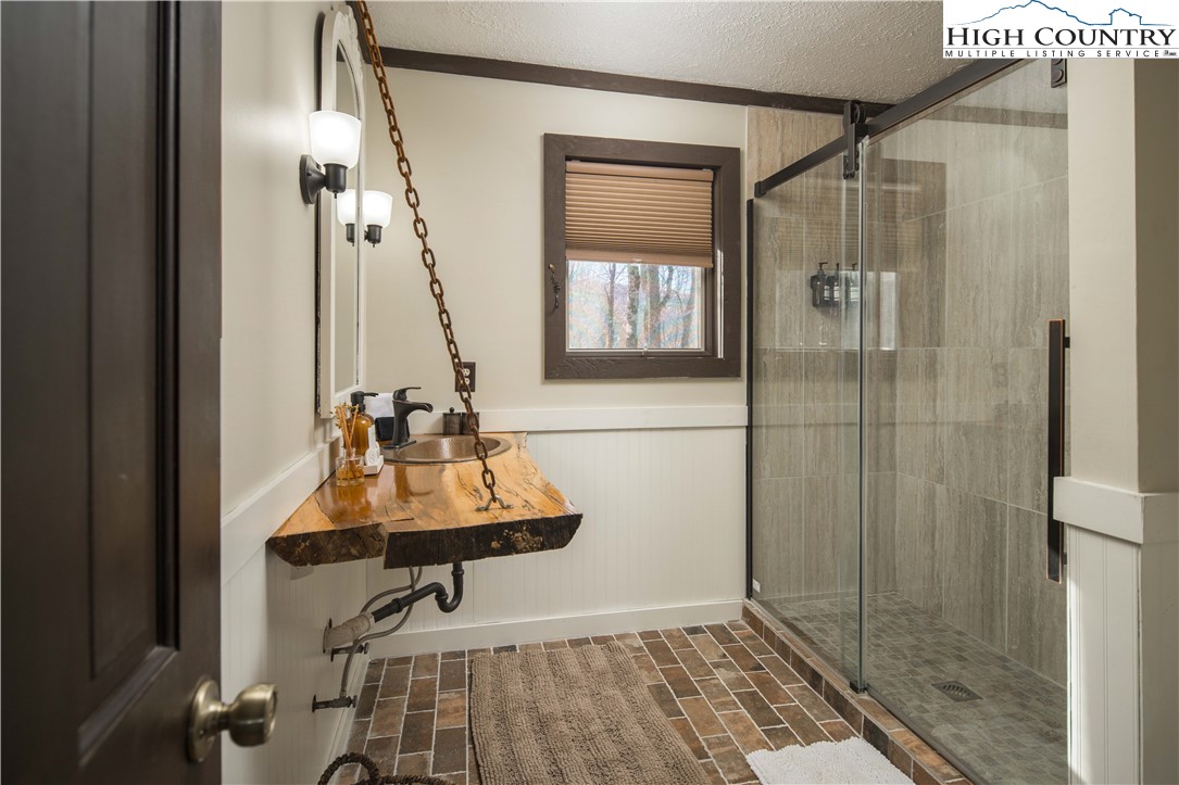 111 Pinnacle Ridge Road Beech Mountain, NC 28604 - Photo 28 of 50 a bathroom with a sink a mirror and shower