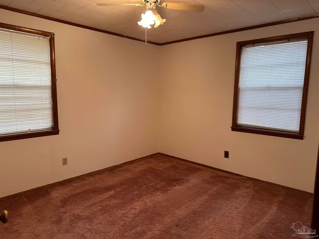 an empty room with a window and a chandelier fan