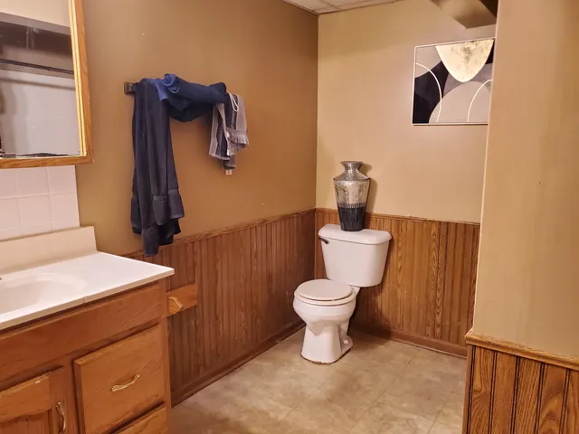 a view of a hallway with wooden floor and a bathroom