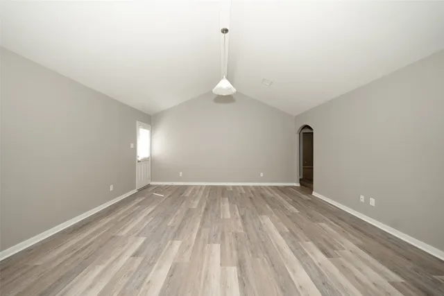 a view of empty room with wooden floor and window