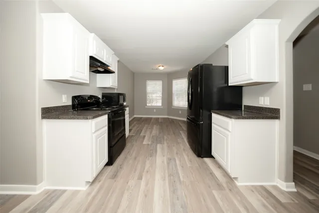 a kitchen with a sink a refrigerator and cabinets