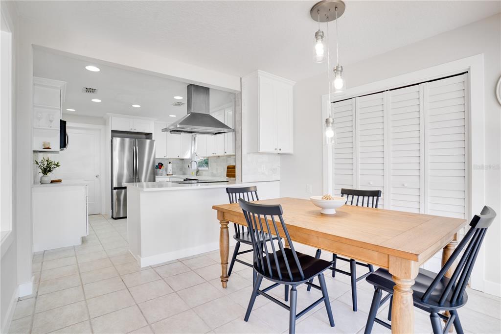 333 12th Avenue Indian Rocks Beach, FL 33785 - Photo 17 of 64 a kitchen with stainless steel appliances kitchen island granite countertop a dining table chairs and white cabinets