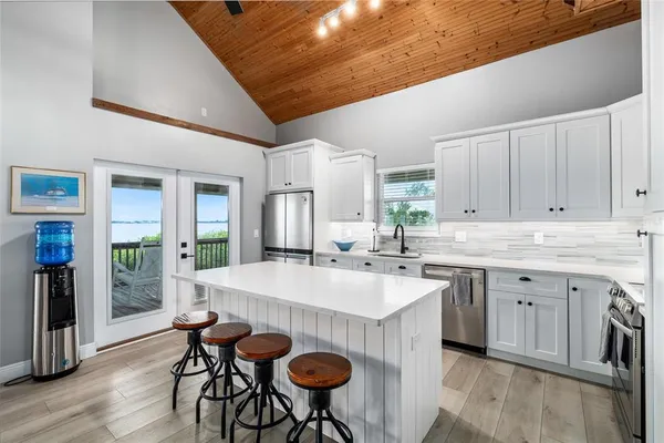a kitchen with stainless steel appliances a dining table chairs refrigerator and cabinets