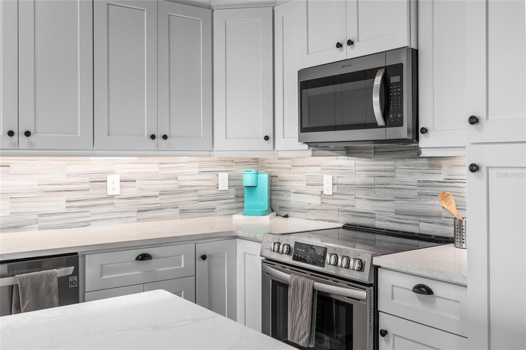 8772 Little Gasparilla Placida, FL 33946 - Photo 27 of 54 a kitchen with stainless steel appliances granite countertop white cabinets and a stove top oven
