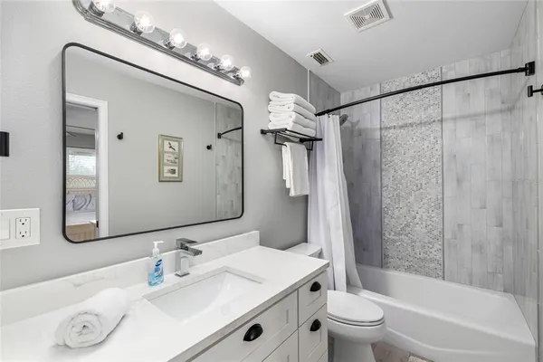 a bathroom with a sink a toilet a mirror a vanity and shower