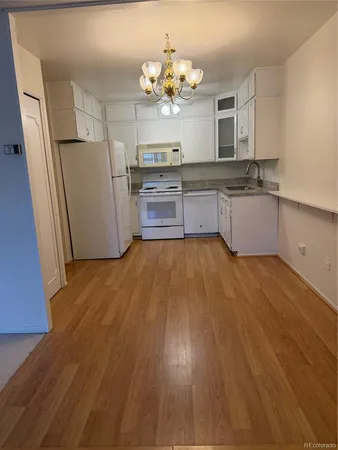 a large kitchen with granite countertop a stove a sink dishwasher a refrigerator and wooden floor