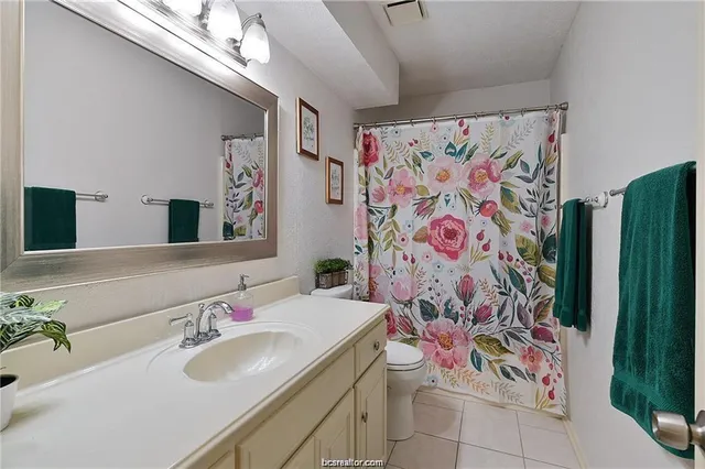 a bathroom with a sink and mirror with shower curtain