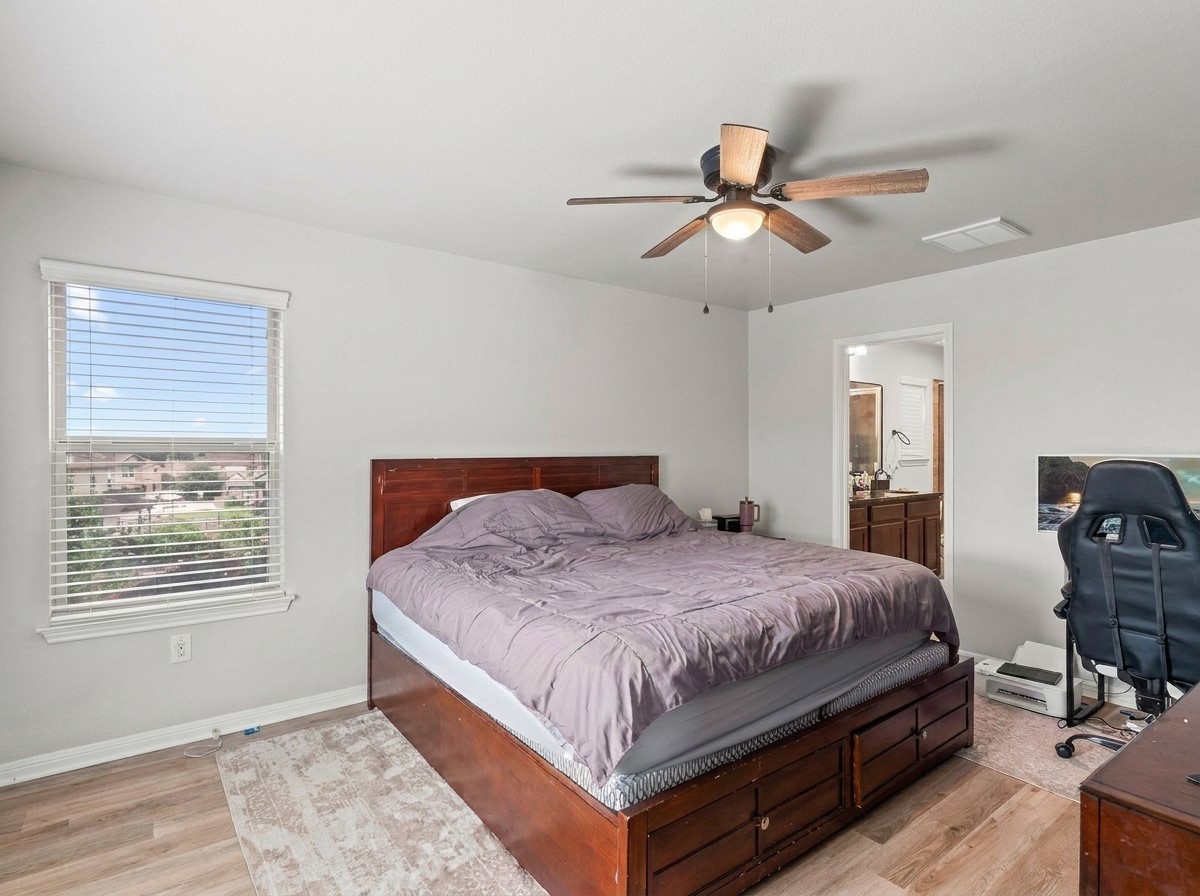 424 Wapiti Road Buda, TX 78610 - Photo 9 of 21 The generously sized bedroom offers a peaceful retreat with light wood flooring and a view of the neighborhood through its window.