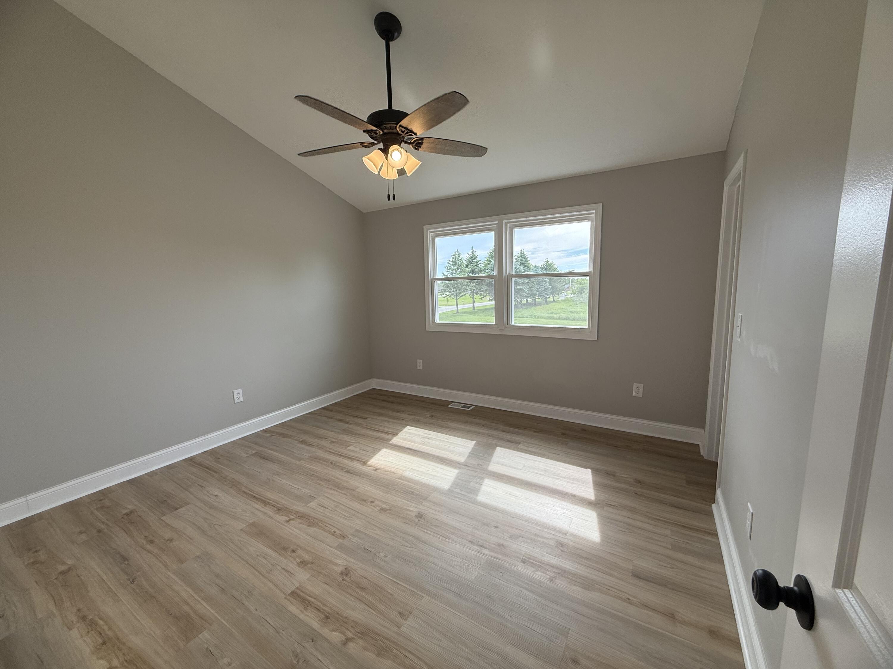 15895 Sherman Street Lowell, IN 46356 - Photo 28 of 36 an empty room with wooden floor chandelier fan and windows