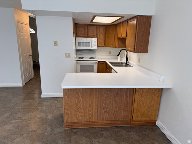 747 Hanover Drive Orem, UT 84058 - Photo 6 of 30 Kitchen featuring wood finish cabinets, light countertops, white appliances, a peninsula, and dark tile patterned flooring