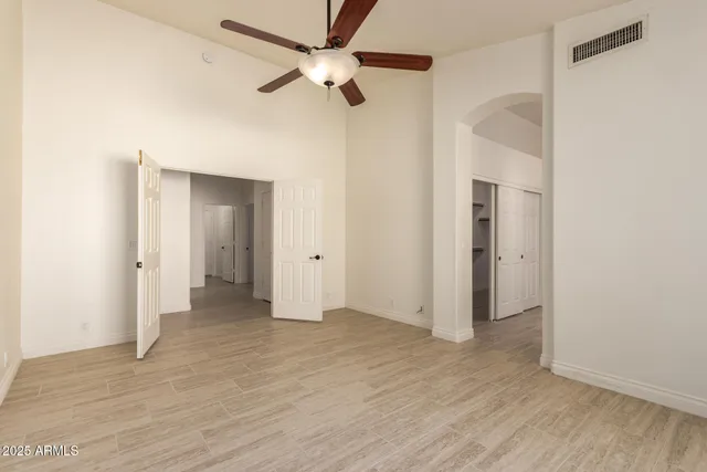 an empty room with wooden floor and a ceiling fan