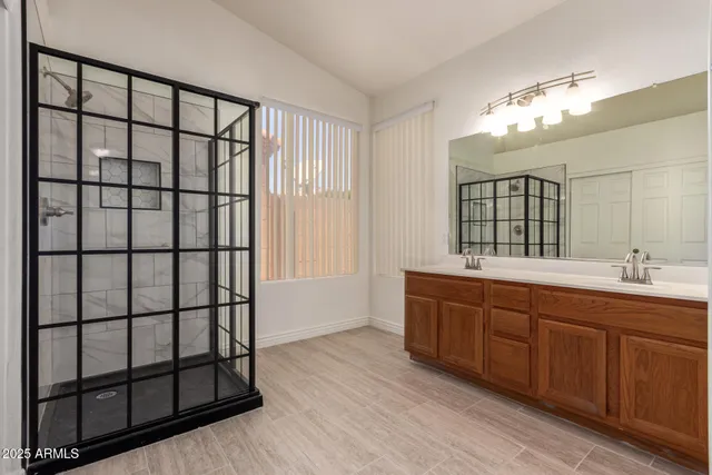 a spacious bathroom with a double vanity sink large mirror and shower