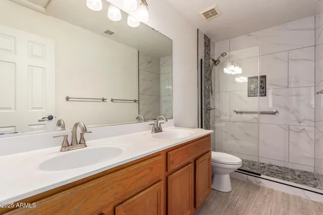 a bathroom with a double vanity sink toilet and shower