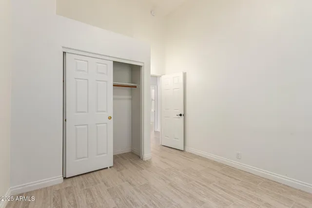 a view of an empty room with wooden floor and closet