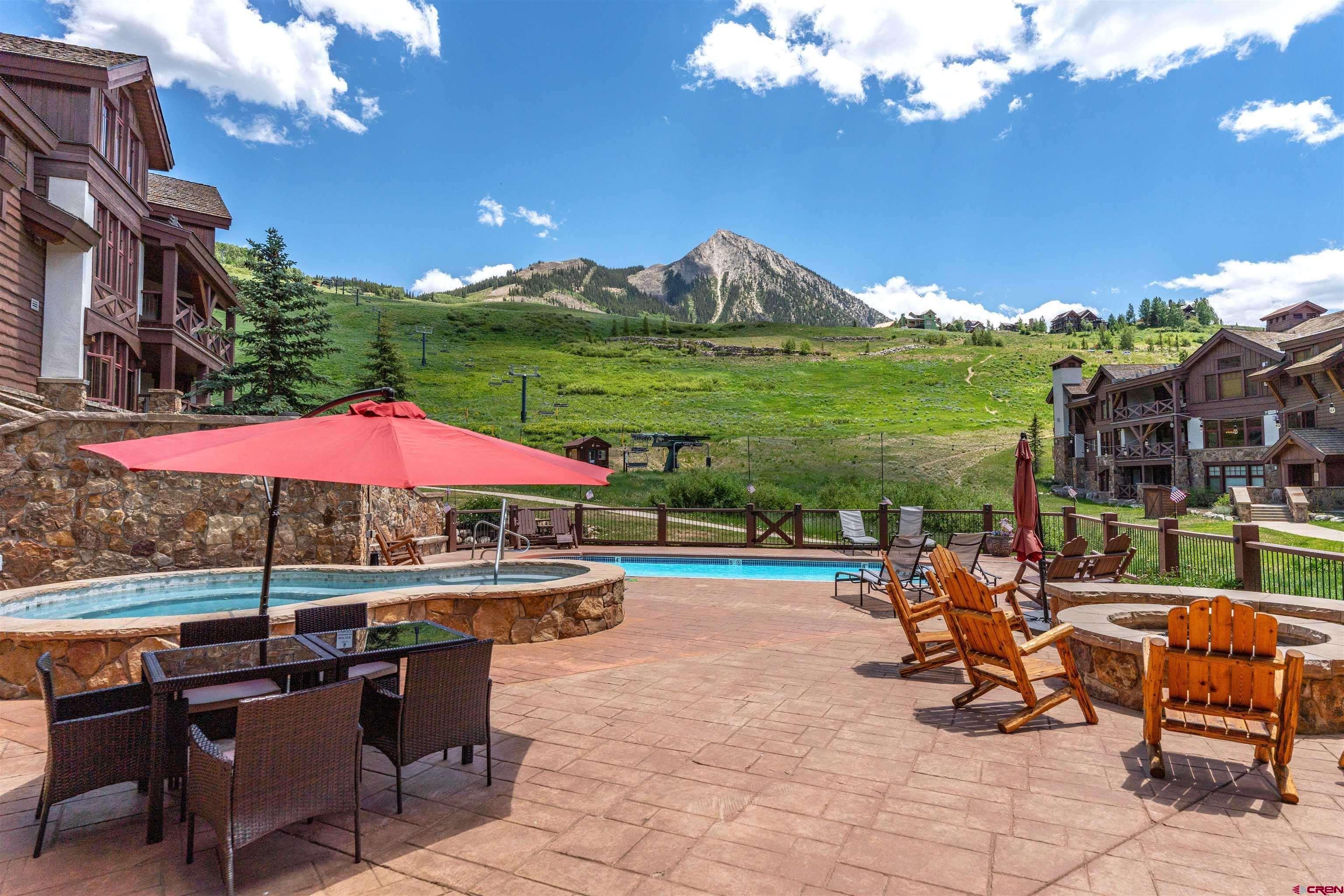 14 Hunter Hill Road, Unit A405 Crested Butte, CO 81225 - Photo 31 of 38 a view of a swimming pool with lawn chairs under an umbrella