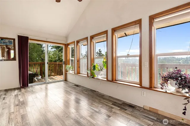 a view of an empty room with a window and wooden floor