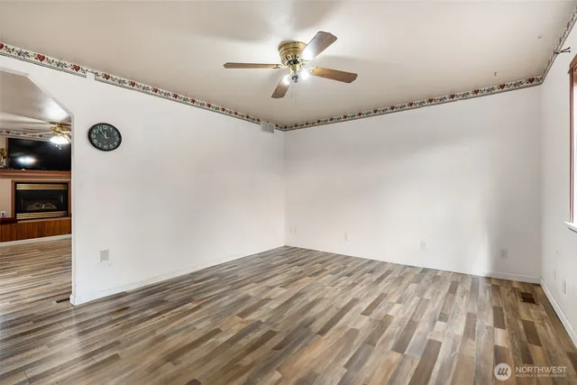 an empty room with wooden floor chandelier fan and windows