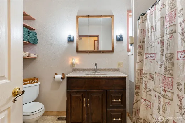 a bathroom with a granite countertop sink a toilet and a mirror