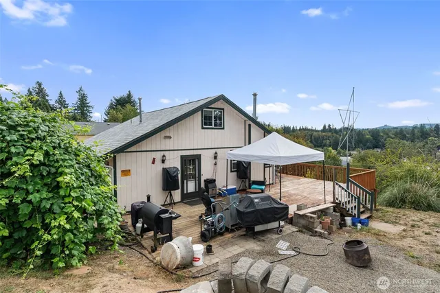 a backyard of a house with table and chairs under an umbrella