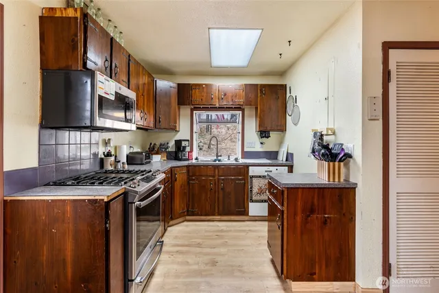 a kitchen with stainless steel appliances granite countertop a stove a sink dishwasher and a refrigerator
