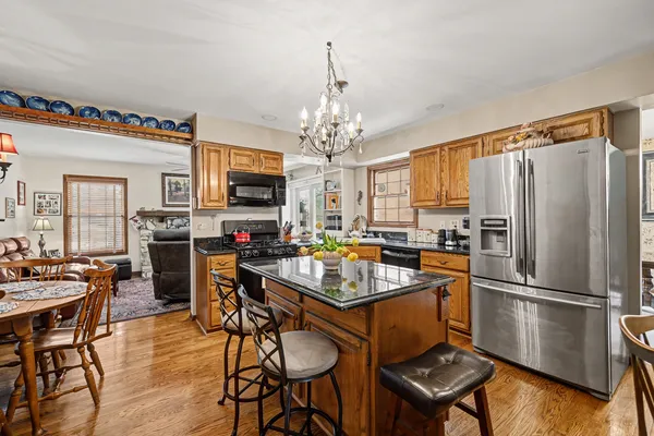 a kitchen with stainless steel appliances granite countertop a refrigerator a stove a sink a dining table and chairs