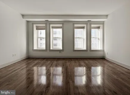 a view of an empty room with wooden floor and window
