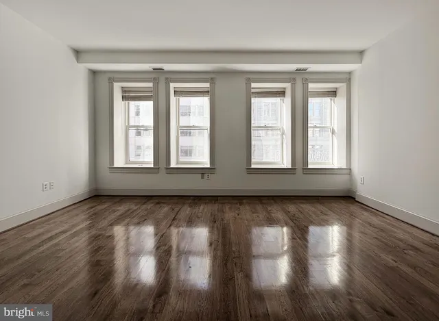 a view of an empty room with wooden floor and window