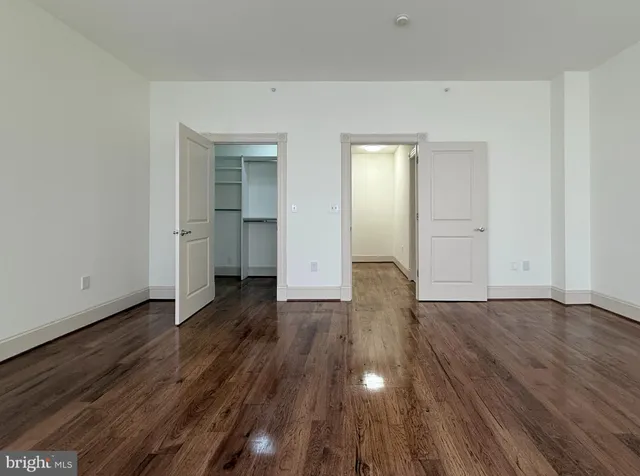 a view of an empty room with wooden floor and closet