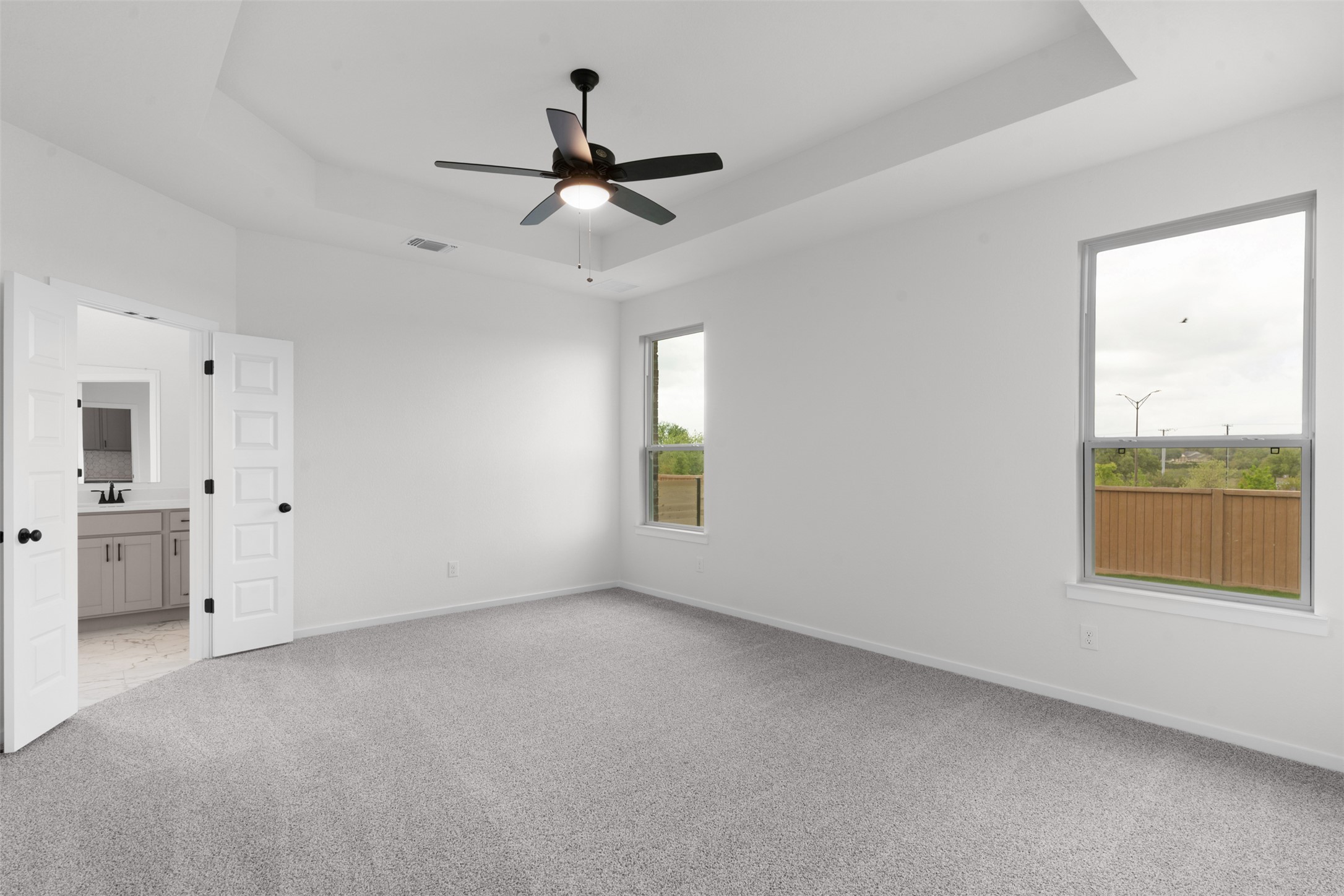 405 Raleigh Drive Georgetown, TX 78633 - Photo 10 of 27 Unfurnished bedroom featuring carpet, a ceiling fan, ensuite bathroom, and a tray ceiling