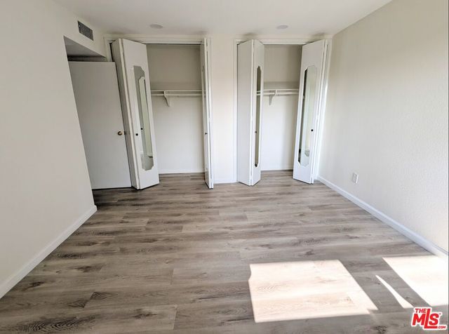 a view of empty room with wooden floor and window