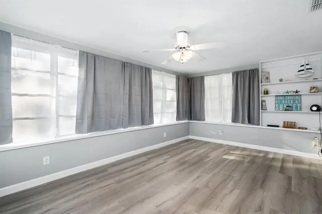 a view of an empty room with a window and wooden floor