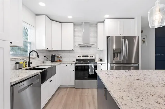 a kitchen with stainless steel appliances granite countertop a sink stove and refrigerator