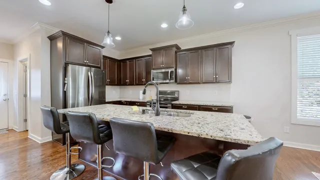a kitchen with stainless steel appliances granite countertop a dining table chairs refrigerator and cabinets