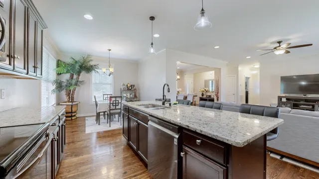 a kitchen with a stove center island wooden floor and living room
