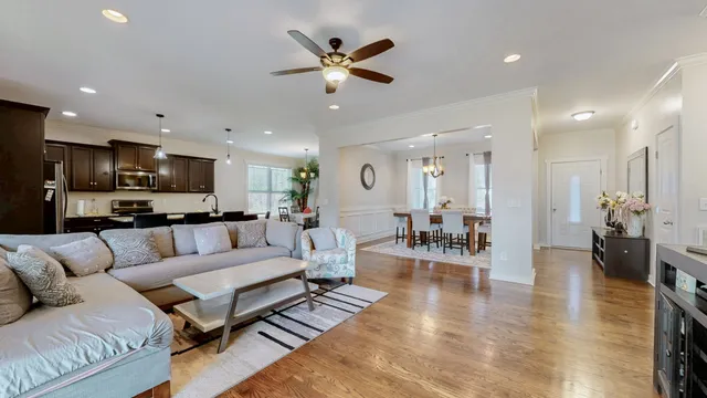 a living room with furniture kitchen view and a wooden floor