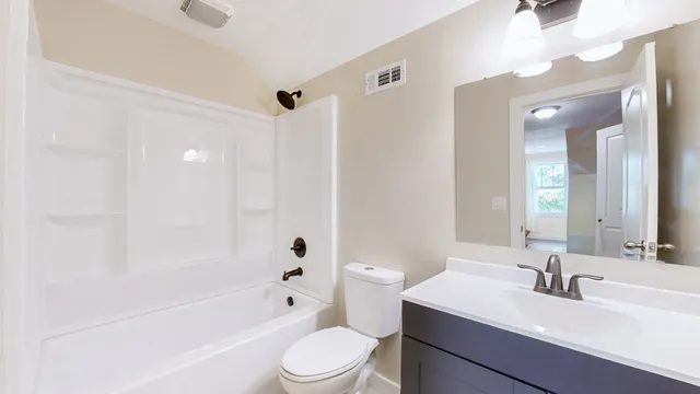 a bathroom with a bathtub shower sink vanity mirror and toilet