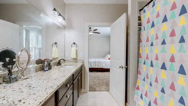 a bathroom with a granite countertop sink a mirror and shower curtain