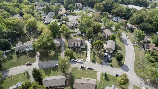 an aerial view of residential houses with outdoor space and trees