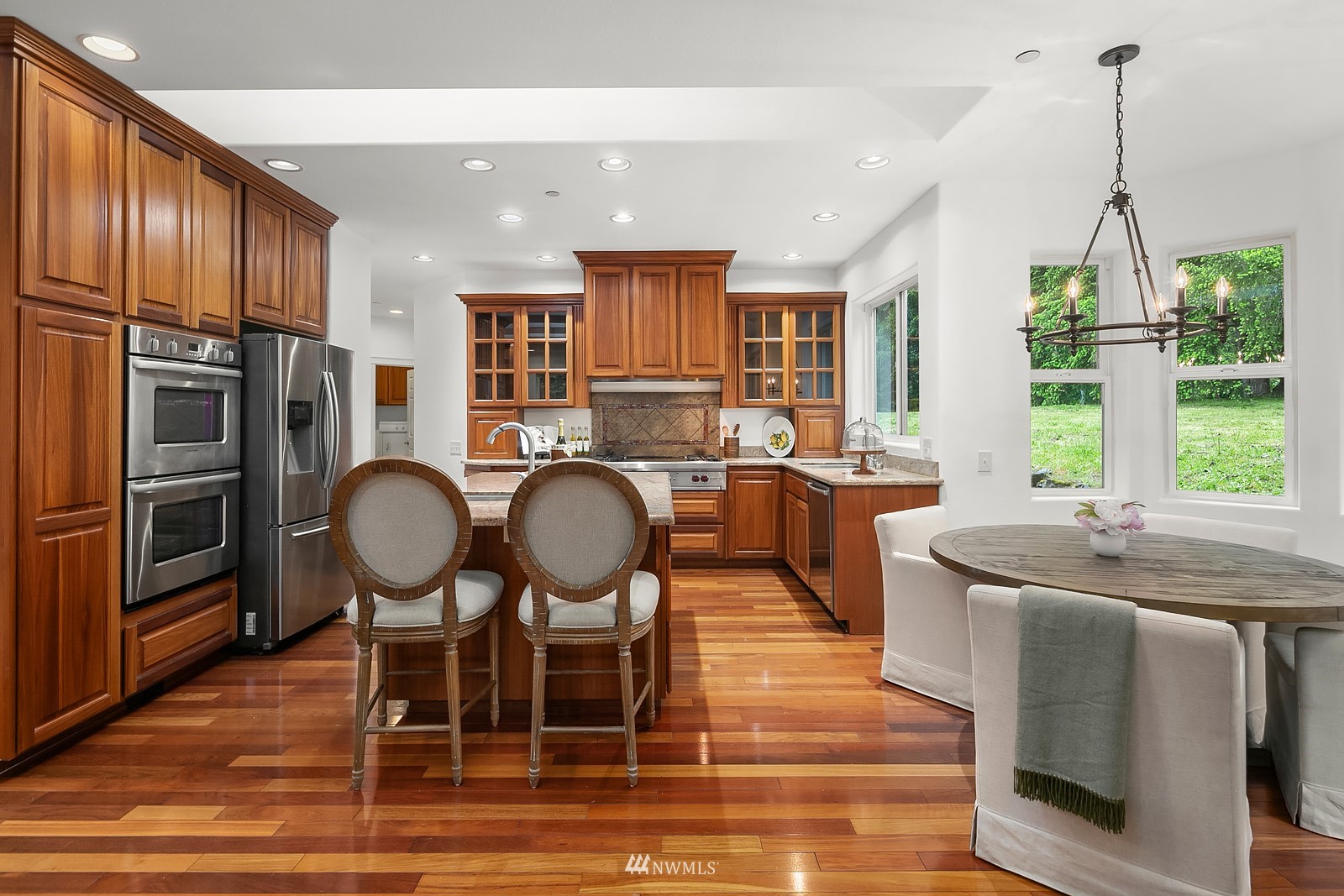 18512 Southeast Petrovitsky Road Renton, WA 98058 - Photo 11 of 40 a kitchen with stainless steel appliances granite countertop a stove a refrigerator a kitchen island a table and chairs with wooden floor